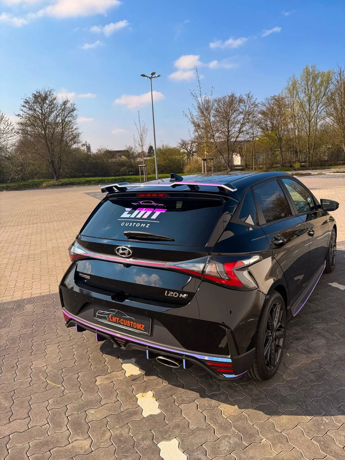 Schwarzer Hyundai i20 N von hinten mit LMT-Customz Heckscheibenaufkleber und schillernden Akzenten am Diffusor